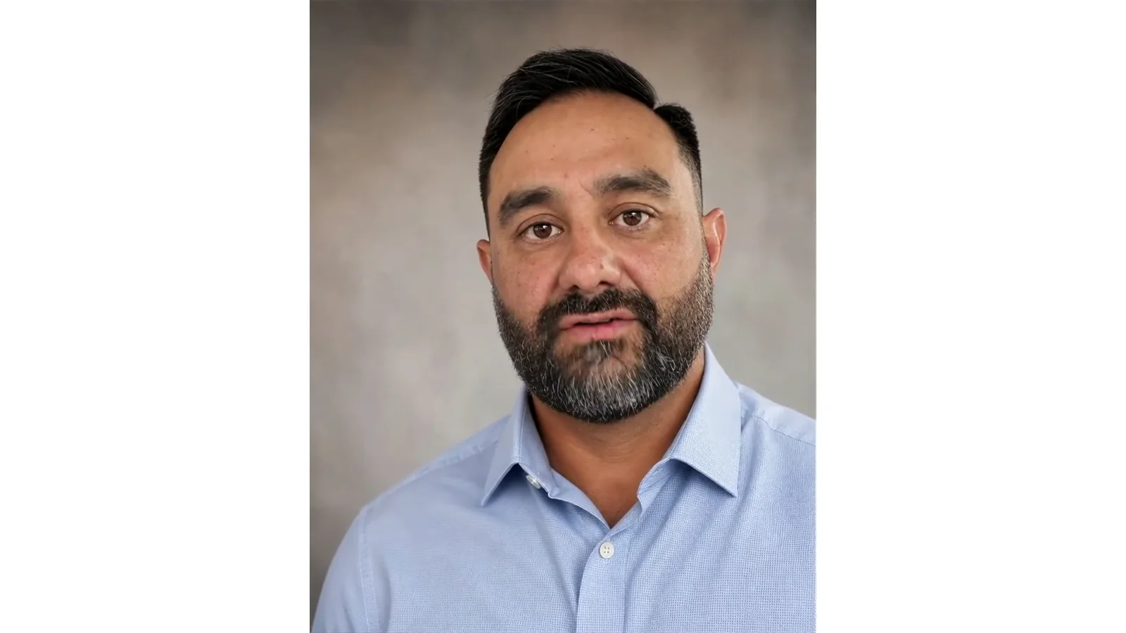 AI Russell, wearing a light blue shirt, against a softly blurred neutral background.